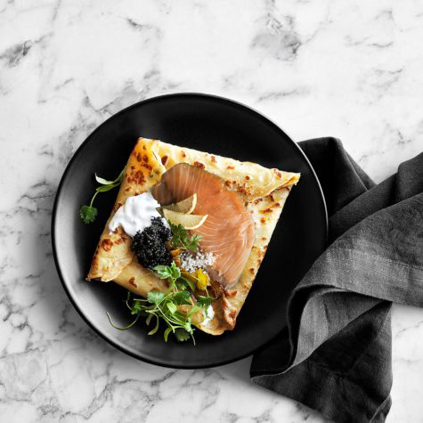 Parisian crêpe with smoked salmon and Royal Ossetra caviar on a black plate